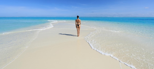 girl model in a black bikini on the white sand by the ocean