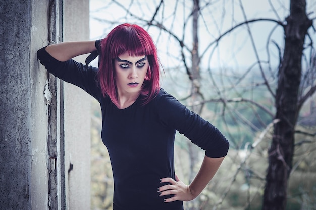 Photo girl model in black with pink hair in an abandoned building