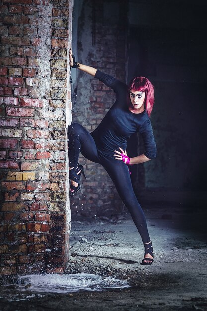 Girl model in black with pink hair in an abandoned building