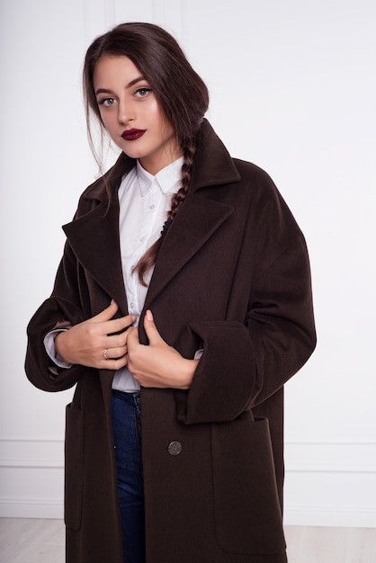 Photo girl model brunette in a long brown coat. posing