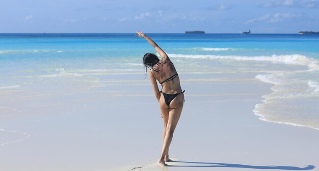 바다의 하얀 모래에 검은 비키니 소녀 모델