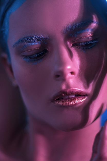 Girl model with bright makeup in neon shades with lowered eyes.