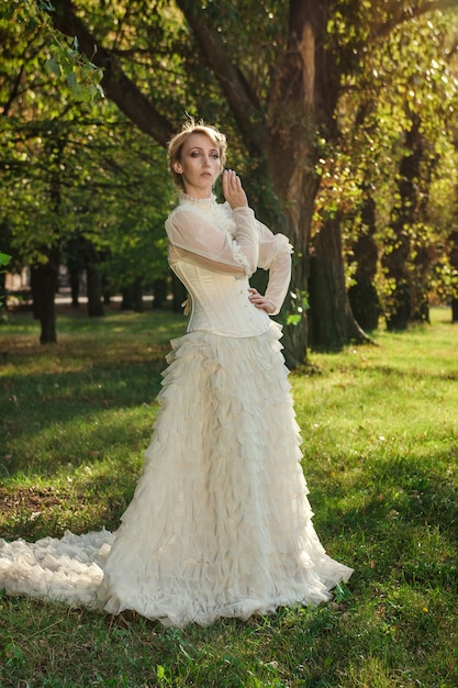 Girl model with white hair in a retro dress with ruffles in a green park