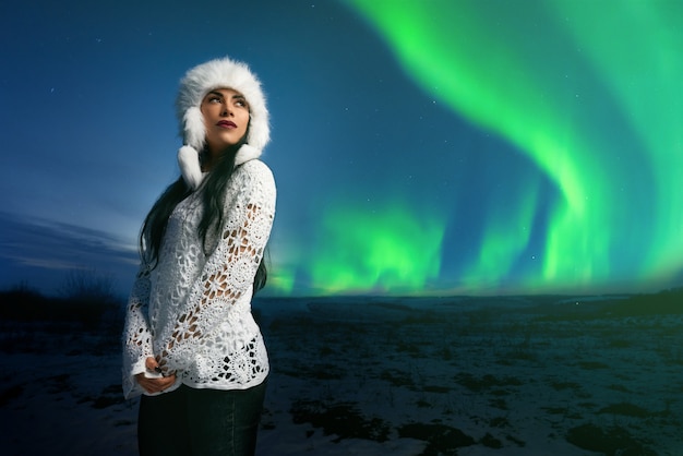 Girl in modern clothing on background of northern lights.