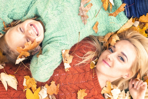 Girl and mom lying on autumn leaves