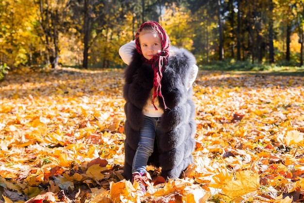 Girl in mom's waistcoat in autumn park