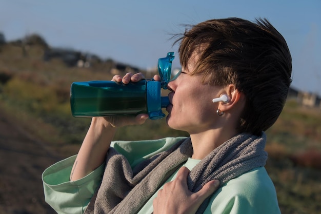 Девушка на утренней пробежке. телефон, бутылка с водой, беспроводная гарнитура для комфортного занятия спортом