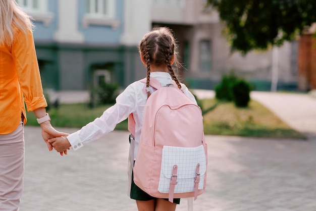 girl and mother hold hands and go from school back to school