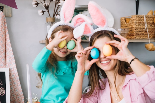 Ragazza e madre che tengono le uova di Pasqua colorate agli occhi