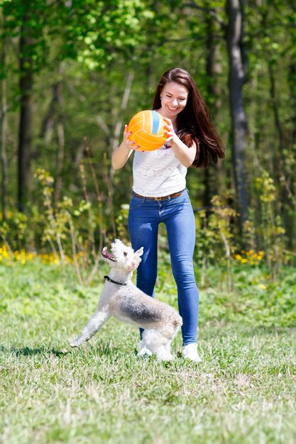 Девушка в движении Мяч тренирует собаку в летнем парке