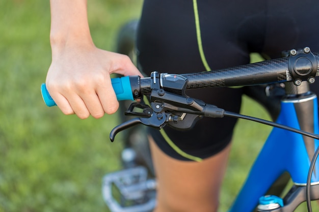 オフロードでマウンテンバイクに乗っている女の子、サイクリストの美しい肖像画、フィットネスの女の子はスポーツウェアでモダンなカーボンファイバーマウンテンバイクに乗っています。