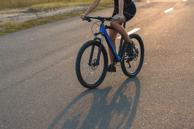 オフロードでマウンテンバイクに乗っている女の子、サイクリストの美しい肖像画、フィットネスの女の子はスポーツウェアでモダンなカーボンファイバーマウンテンバイクに乗っています。