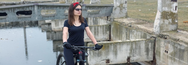 오프로드에서 산악 자전거를 탄 소녀 비오는 날씨에 자전거 타는 사람의 아름다운 초상화 휘트니스 소녀는 스포츠웨어에 현대 탄소 섬유 산악 자전거를 타고 빨간 두건을 입은 소녀의 근접 촬영 초상화