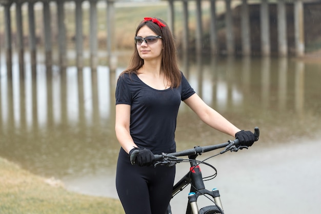 雨天のサイクリストのオフロードの美しい肖像画のマウンテンバイクの女の子