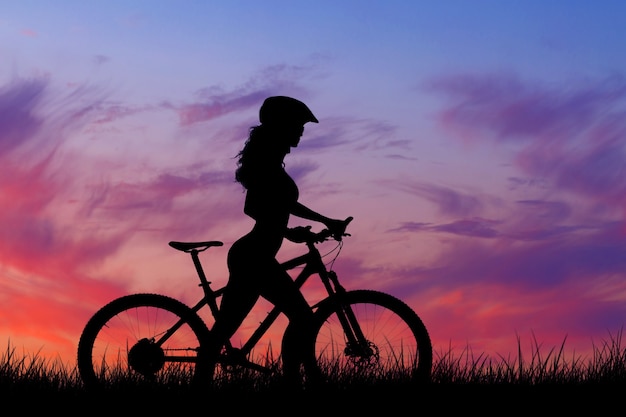오프로드에서 산악 자전거를 탄 소녀, 일몰 시 자전거 타는 사람의 아름다운 초상화
