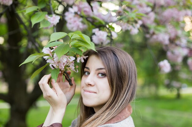 咲く桜の近くの女の子。春はこれから。桜。夕暮れの桜。日没時の肖像画
