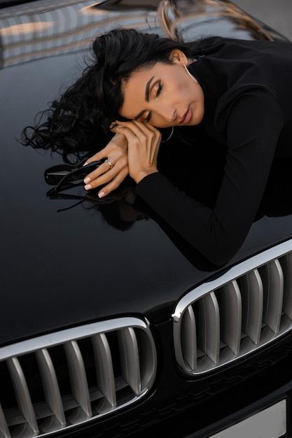 A girl near the car in a black dress