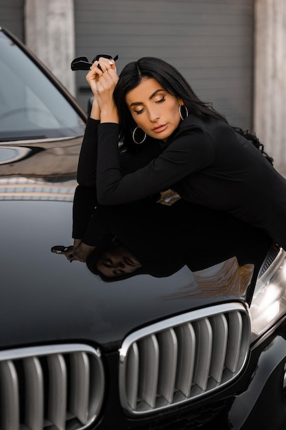 A girl near the car in a black dress