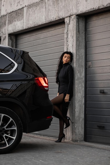 A girl near the car in a black dress