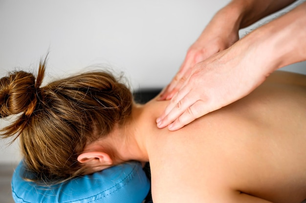 Girl during neck and shoulders massage in spa salon Masseur hands doing care body therapy procedure for young woman wellness and relaxation