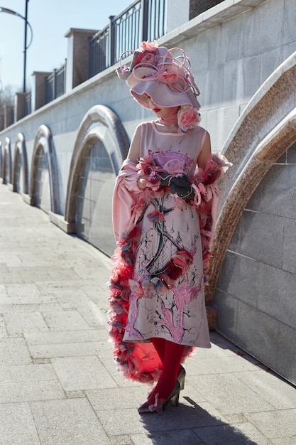 Girl new fashion Vogue creative clothes posing outdoors, pink dress and hat, ethnic clothing