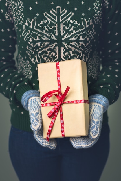 A girl in a New Year's sweater holds a present.