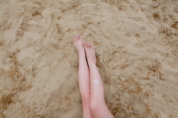 Фото Девушка с масляным спреем для загара защищает ноги от солнечных лучей, нанося солнцезащитный лосьон для загара