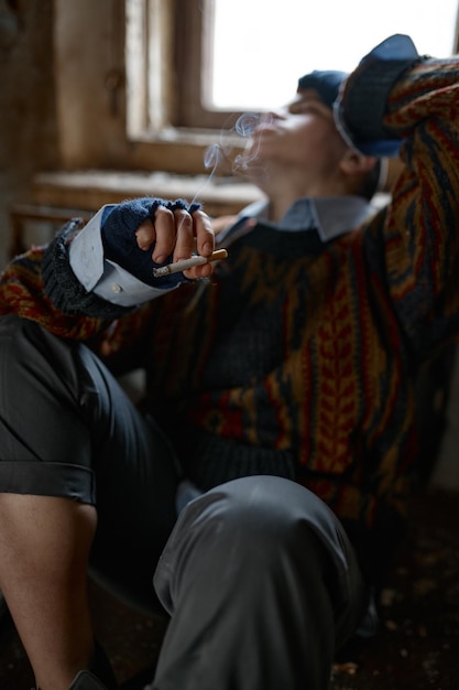 Девушка в старой грязной, рваной одежде курит сигарету, избирательный фокус