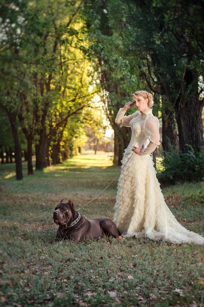 Girl in an old dress with ruffles and a big dark dog