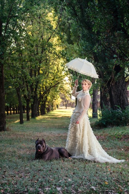 Girl in an old dress with ruffles and a big dark dog