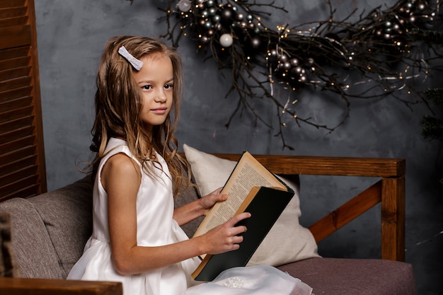 Girl opening book in room decorated for Christmas