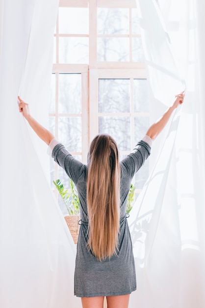 Girl opening curtains