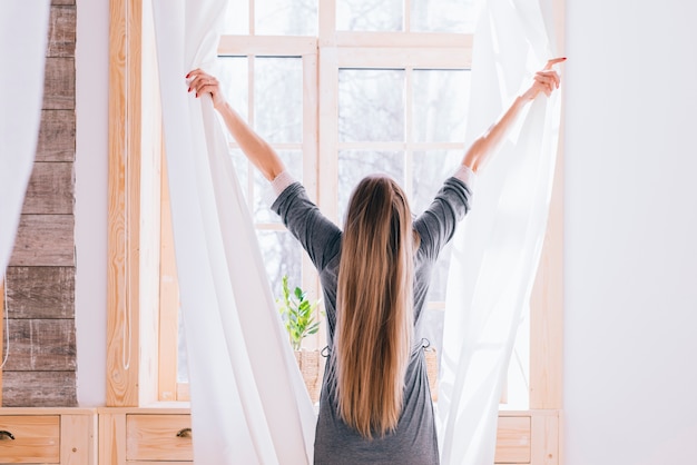 Girl opening curtains