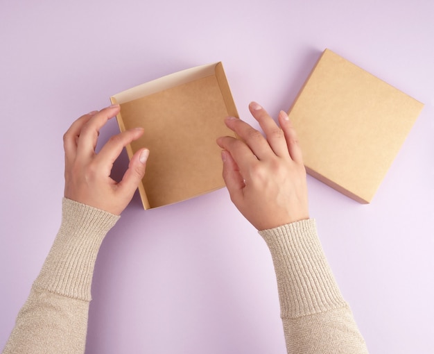 Girl opens a brown square box on a purple background