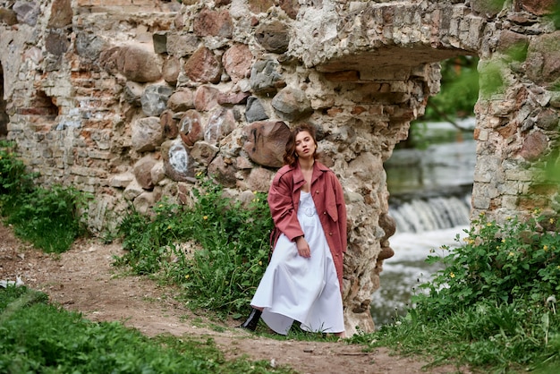 A girl opposite an old ruined building near a stormy river