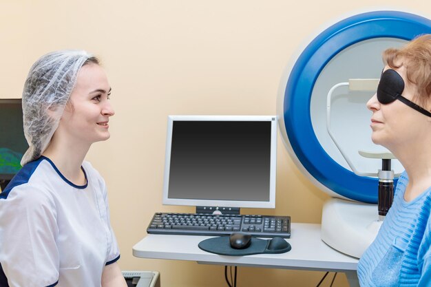Девушка-оптометрик осматривает глаза пациента с помощью специального современного оборудования