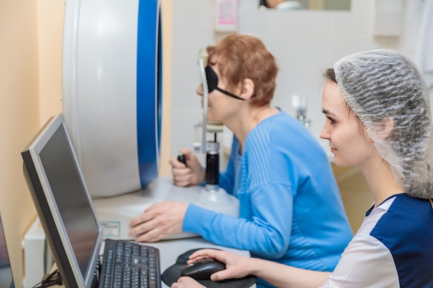 A girl optometrist examines the eyes of a patient using special modern equipment