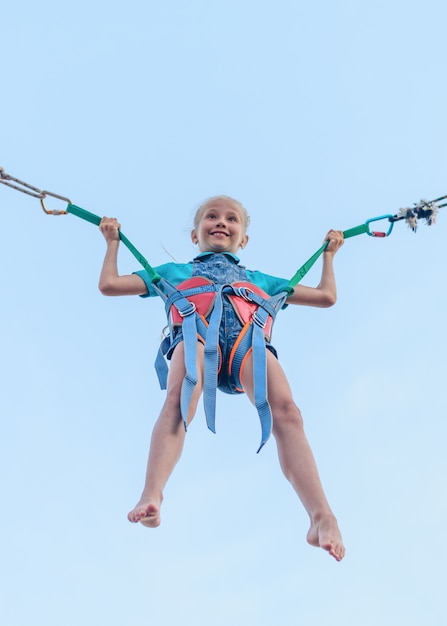 A girl in overalls jumping on a stretch of belts