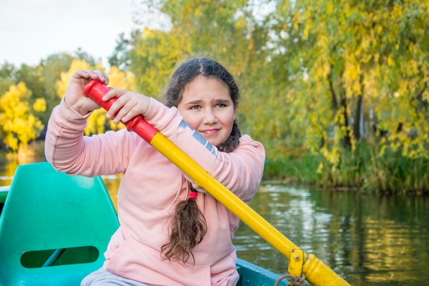 A girl paddles a boat on a river.