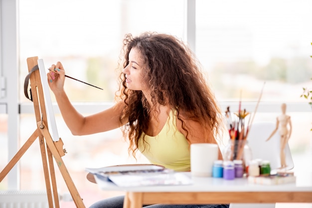 Girl painter painting indoors