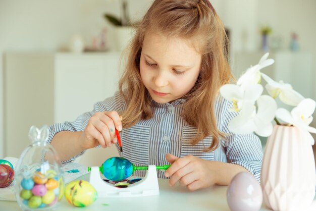 Girl painting easter eggs at table