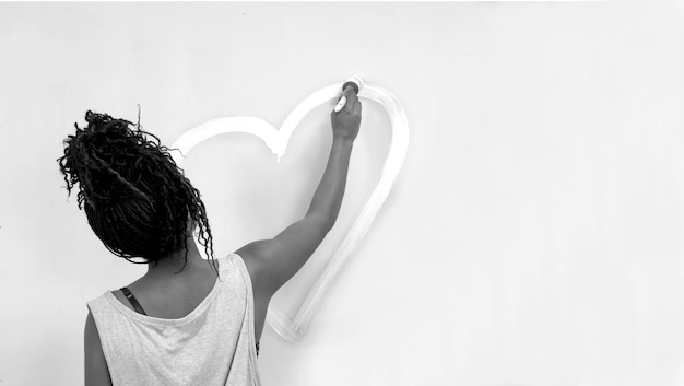 Girl painting a heart on the wall, african girl