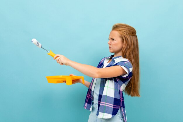 Girl paints a light blue wall