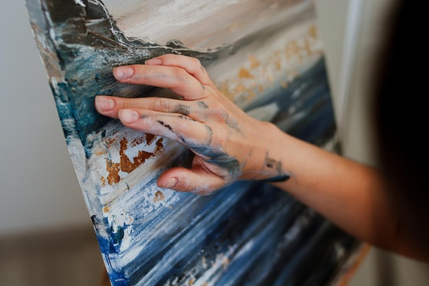 The girl paints a picture with acrylic paints with her fingers. The process of creating a picture.