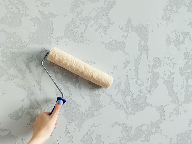 girl paints the wall with white paint female hand with wall paint roller close up with copy space