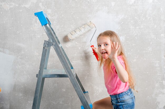 girl paints the walls with a roller in the room Family renovation house Home repair and renovation