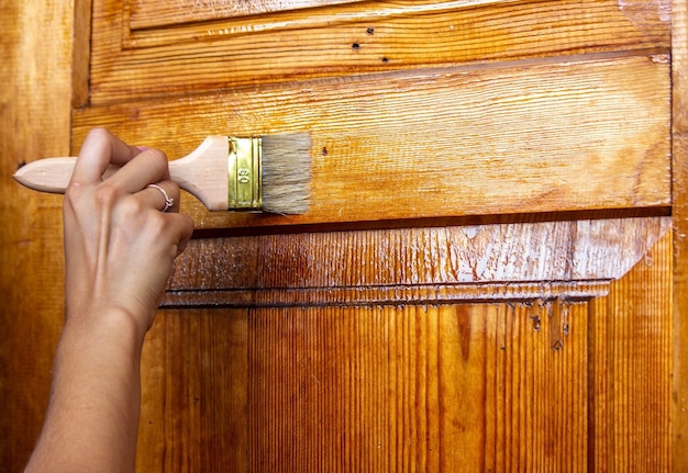 girl paints a wooden door. Summer work in the garden. Selective focus