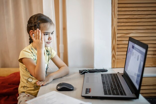 オンラインレッスン中に勉強しているパジャマパンツの女の子