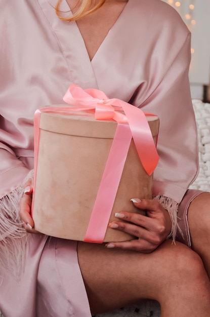 Girl in pajamas in the morning opens a gift in a box