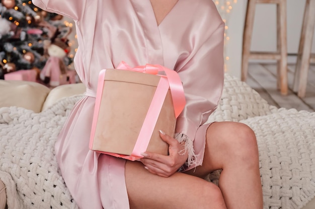 Girl in pajamas in the morning opens a gift in a box